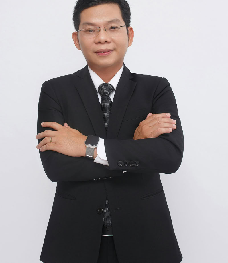 Elegant businessman in a black suit posing confidently with arms crossed in a studio setting.